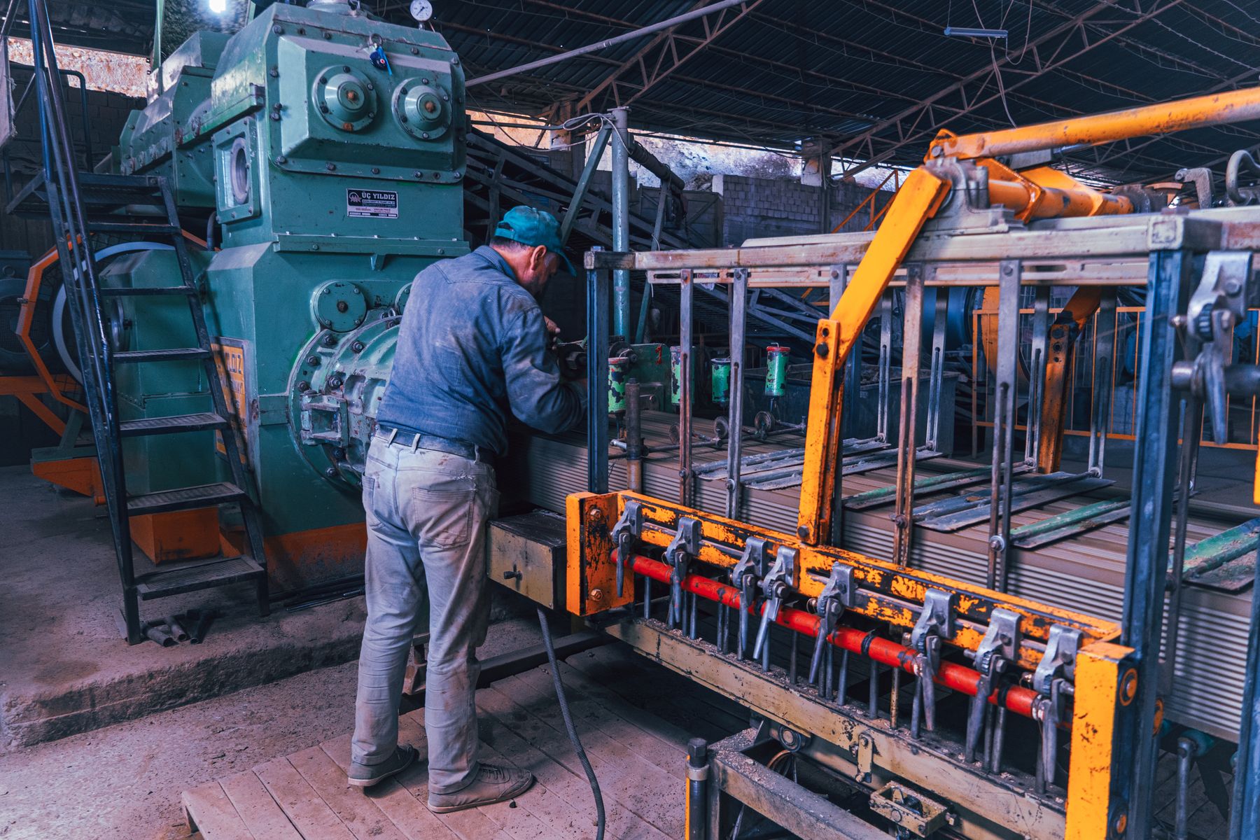 Real photograph of a worker operating large machinery on a factory floor